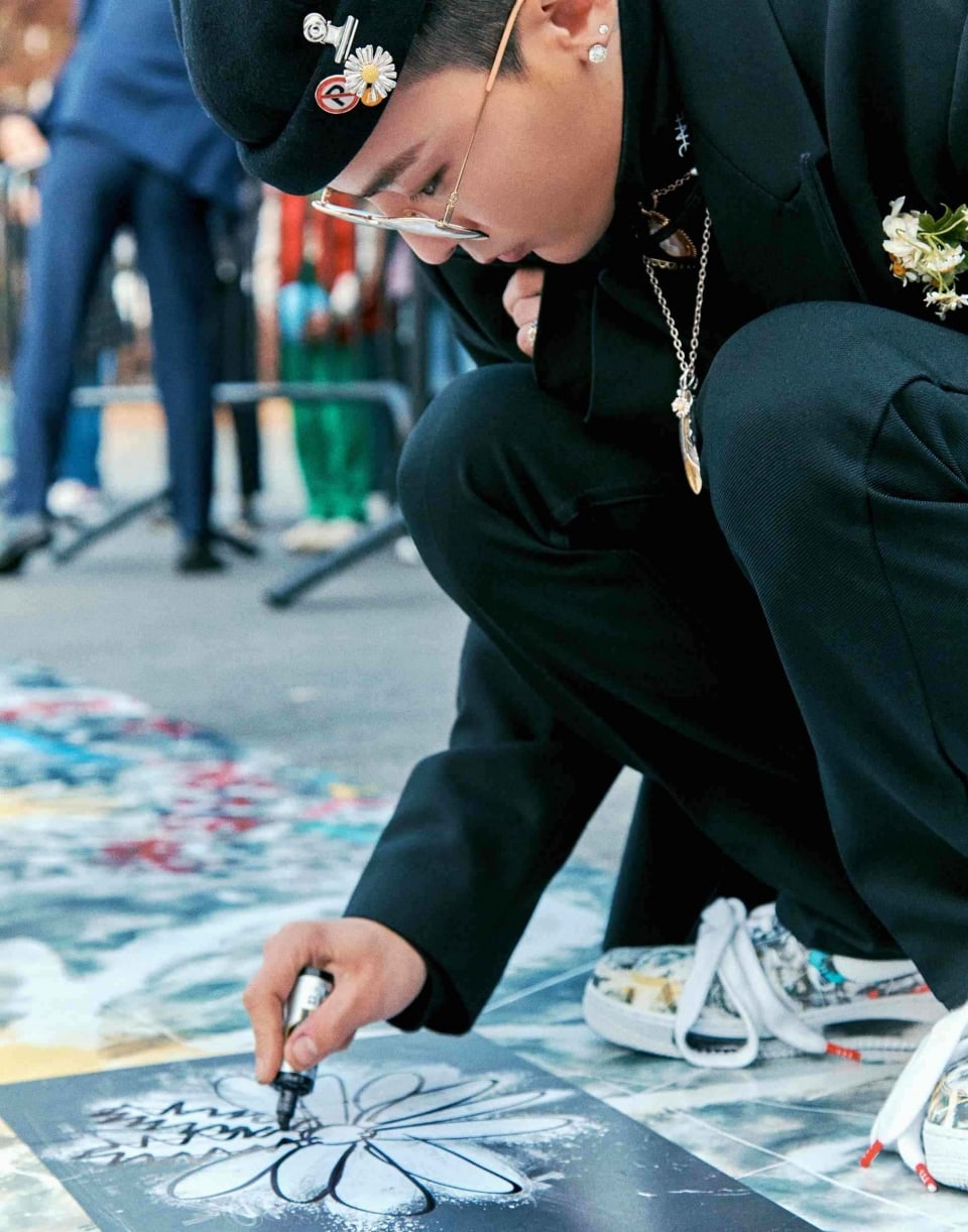 G-Dragon tampak mengimbuhkan bunga daisy di lantai lapangan basket